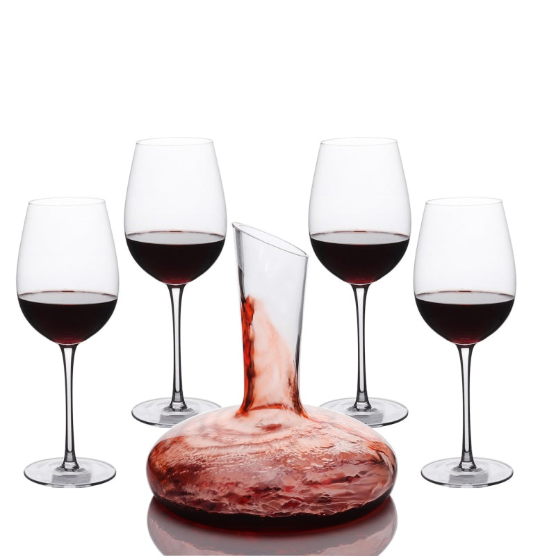 Carafe à décanter remplie de vin rouge entourée de quatre verres à pied
