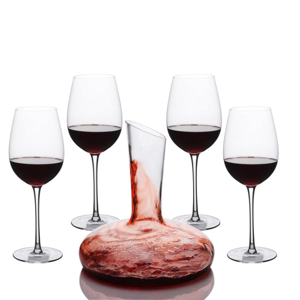 Carafe à décanter remplie de vin rouge entourée de quatre verres à pied