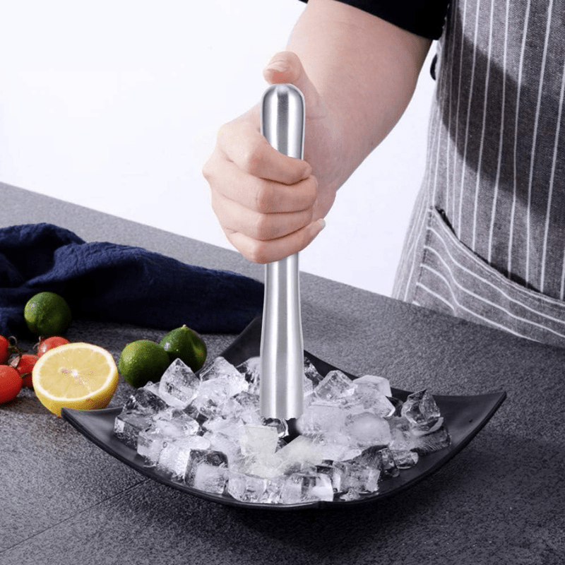 Pilon cocktail en acier inoxydable posé sur un plan de travail, accessoire essentiel du kit cocktail professionnel