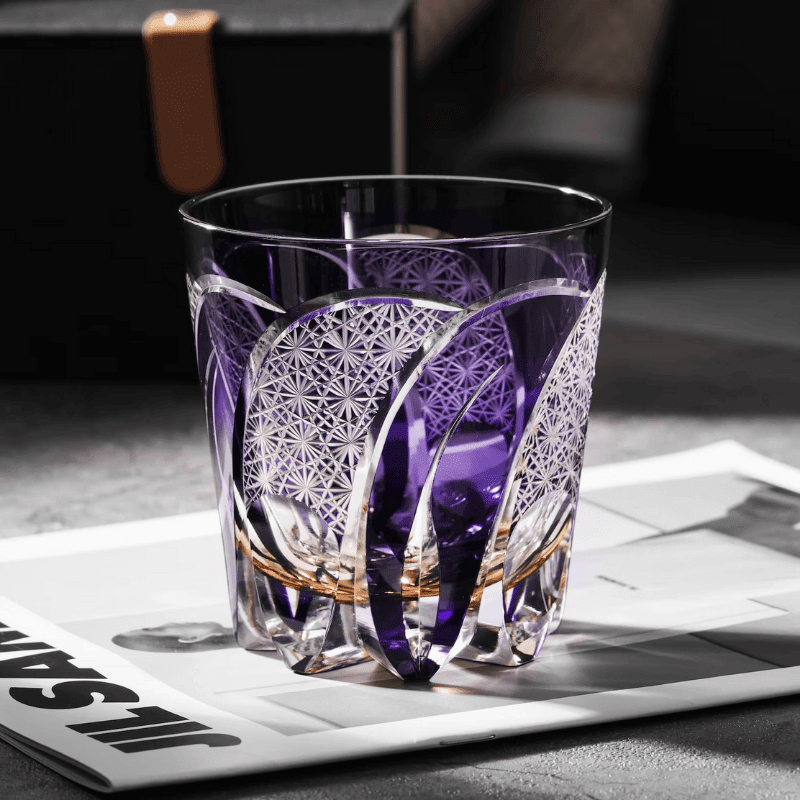 Verre à whisky en cristal violet taillé à la main, détail des facettes et reflets lumineux
