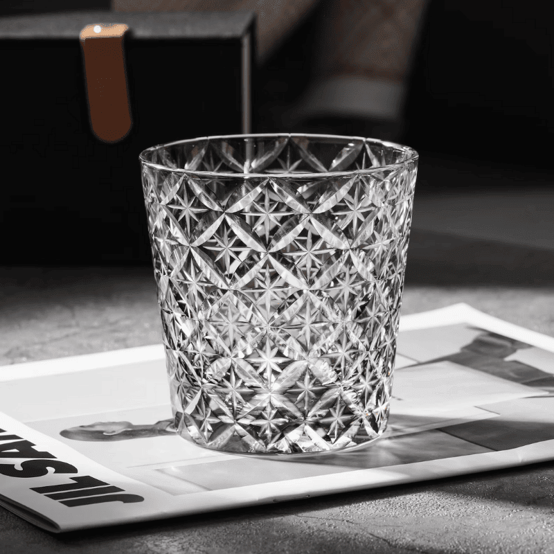 Verre à whisky en cristal taillé posé sur une surface sombre, détail du motif gravé